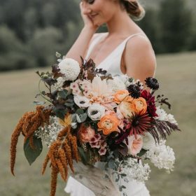 side view portrait of a bride with her left hand holding a bouquet and her right hand on her cheek