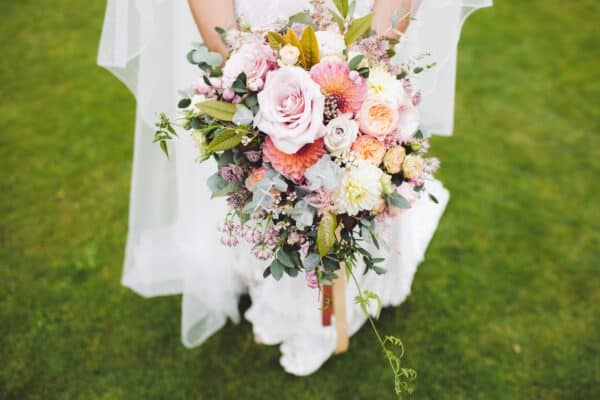 Newlywed Woman Holding Bouquet Standing on Green Grass Newlywed Woman Holding Bouquet Standing on Green Grass